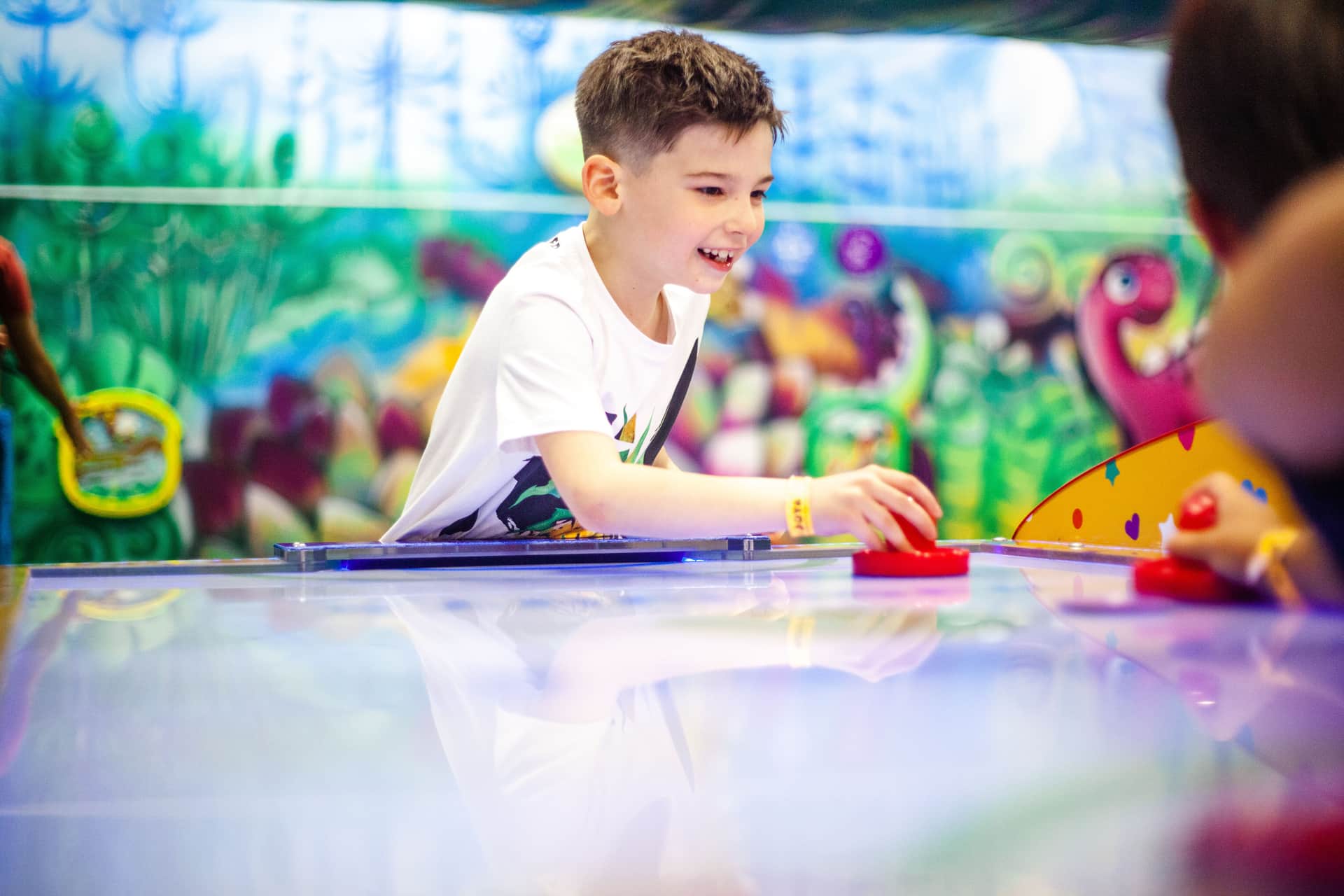 A young boy playing air hockey indoors
