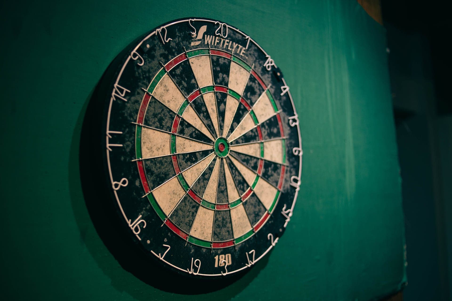 A dartboard mounted on a wall with darts in the board