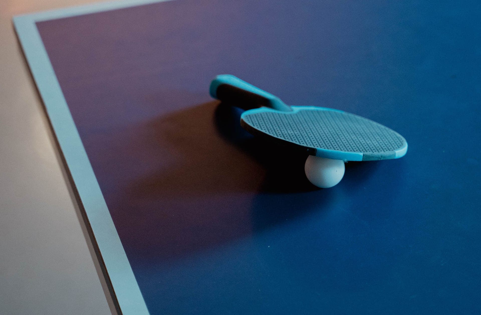A table tennis paddle and ball on a blue table